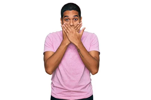 カジュアルなピンクのTシャツを着た若いハンサムなヒスパニック系の男性がミスのために手で口をカバーショックを受けました 秘密の概念 — ストック写真