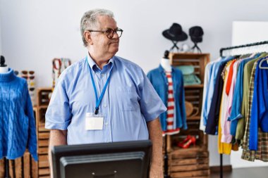 Gri saçlı, perakende mağazasında müdürlük yapan, yüzünde gülümsemeyle yan yana bakan son sınıf öğrencisi, doğal bir ifade. Kendinden emin gülen. 