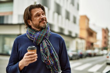 Orta yaşlı yakışıklı adam kasabada bir fincan kahve içiyor.