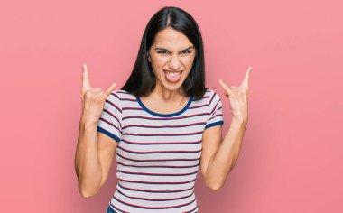 Sıradan çizgili tişört giyen, çılgın bir ifadeyle bağıran genç İspanyol kız elleri havada rock sembolü yapıyor. Müzik yıldızı. ağır kavram. 