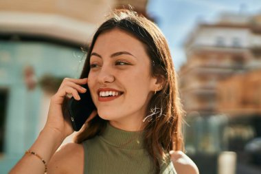 Beyaz kız gülümsüyor. Şehirdeki akıllı telefondan konuşuyor..