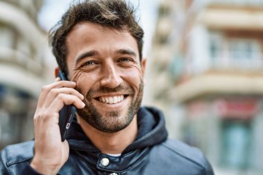 Sakallı yakışıklı, dışarıda mutlu bir şekilde gülümseyen telefonda konuşan adam.