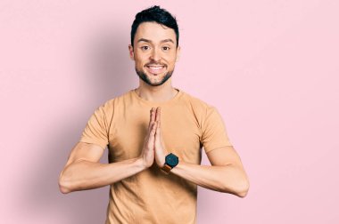 Sakallı, sıradan tişörtlü, elleri birarada dua eden, affedilmek isteyen, kendine güvenen İspanyol bir adam.. 