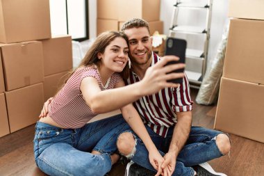 Mutlu gülümseyen beyaz bir çift yeni evdeki akıllı telefonun yanında selfie çekiyor..