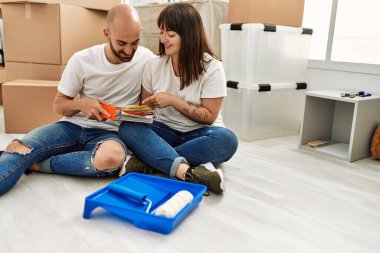 Genç İspanyol çift mutlu bir şekilde gülümsüyor. Yeni evinde boya rengi seçiyor..