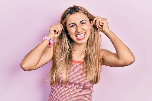 Yazlık tişört giyen güzel İspanyol kadın gülümsüyor kulakları parmaklarıyla çekiyor, komik bir jest. deneme sorunu 