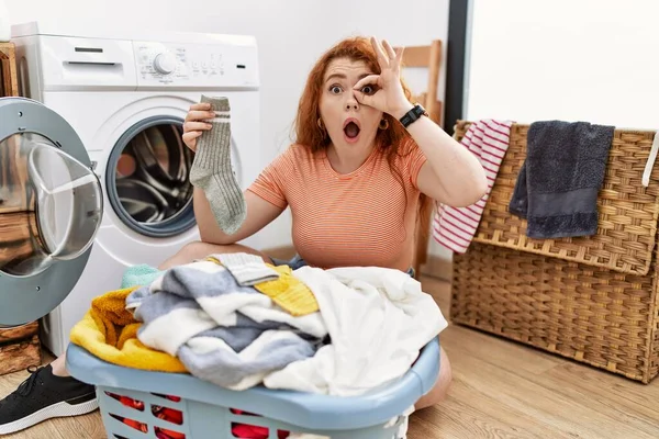 若い赤毛の女性の洗濯機に汚れた洗濯機を行う をジェスチャー驚きの顔でショックを受け 目の指を介して見ている 信じられない表現 — ストック写真