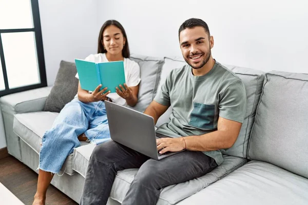 Jovem Casal Latino Usando Laptop Livro Leitura Casa — Fotografia de Stock