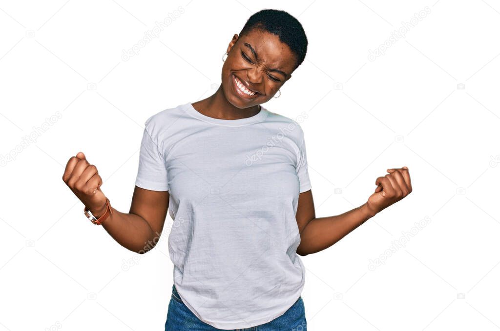 Young african american woman wearing casual white t shirt very happy and excited doing winner gesture with arms raised, smiling and screaming for success. celebration concept. 