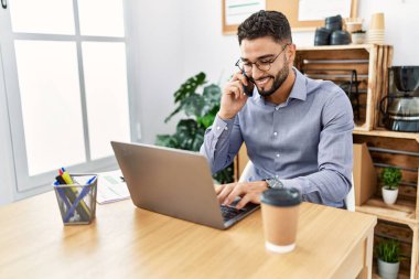 Ofiste çalışırken bilgisayarla konuşan genç bir Arap.