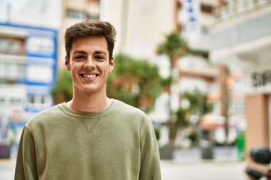 Genç İspanyol adam gülümseyerek şehirde mutlu mesut dikiliyor..