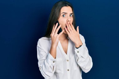 Genç esmer ergen, akıllı telefonla konuşuyor ağzını eliyle kapatıyor, şok geçiriyor ve hata yapmaktan korkuyor. şaşırmış ifade 