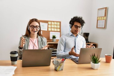 Ofiste laptopla görüntülü arama yaptığı için mutlu gülümseyen iki çağrı merkezi ajanı..