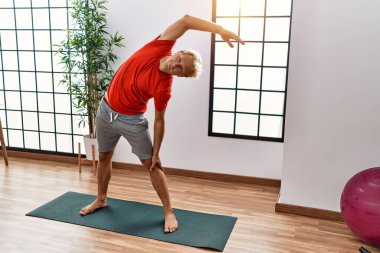 Spor merkezinde esneme hareketleri yapan beyaz bir genç.