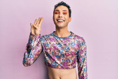 Makyaj giysileri giymiş yakışıklı bir adam dört numarayı gösterip işaret ederken kendine güvenen ve mutlu bir şekilde gülümsüyor.. 