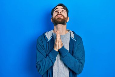 Sakallı, sıradan bir kazak giyen, elleri bağlı yalvaran ve dua eden beyaz bir adam yüzünde umut ifadesi olan çok duygusal ve endişeli bir ifade var. Yalvarıyor. 