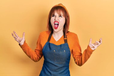 Kızıl saçlı genç bir kadın deli gibi bağırıyor, bağırıyor ve agresif bir ifade ve kollarla bağırıyor. hüsran kavramı. 