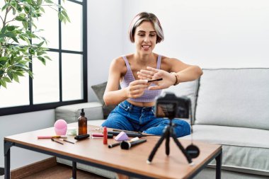 Makyaj hocası olan beyaz bir kız evdeki kanepede oturuyor..