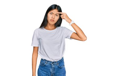 Gayri resmi beyaz tişört giyen genç Asyalı güzel bir kadın alnındaki sivilceden mutsuz olduğunu gösteriyor. Siyah noktalı çirkin bir enfeksiyon. sivilce ve deri problemi 