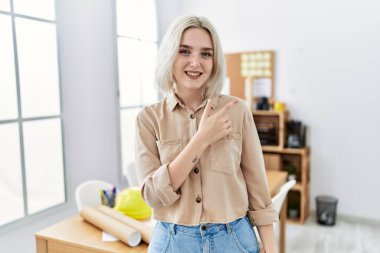 İnşaat ofisindeki genç, güzel, beyaz bir kadın. Yüzünde mutlu ve doğal bir ifadeyle elleri ve parmaklarıyla yüzünü gösteren bir gülümseme. 