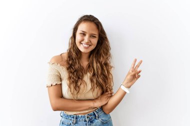 Güzel İspanyol kadın, arka planda dikilirken kameraya bakıp gülümseyen ve zafer işareti yapan. İki numara.. 