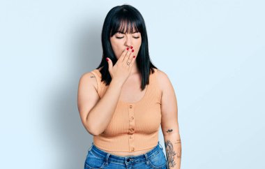 Latin kökenli genç ve iri yarı bir kadın gündelik kıyafetler giymekten sıkılmış. Ağzı eliyle kapatmaktan sıkılmış. Huzursuz ve uykulu.. 