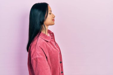 Burnunda piercing olan güzel İspanyol bir kadın. Sıradan pembe bir ceket giyiyor. Yan tarafa bakıyor.. 