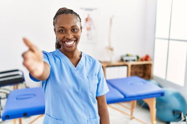 Saçları örgülü siyah bir kadın ağrı giderme kliniğinde çalışıyor. Dostane bir şekilde el sıkışarak selamlama ve hoş geldin diyorlar. başarılı iş. 