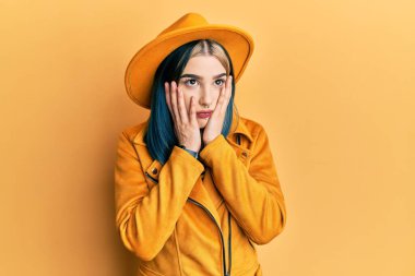 Sarı şapka ve deri ceket giyen genç modern kız yorgun eller yüzünü kapatıyor, depresyon ve üzüntü, sorun yüzünden üzgün ve sinirli. 