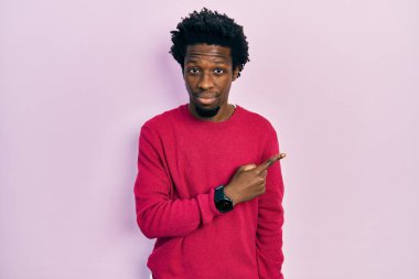 Genç Afro-Amerikalı, günlük kıyafetler giymiş, elini kaldırmış, ciddi ve sakin bir yüz ifadesi sergiliyor. 