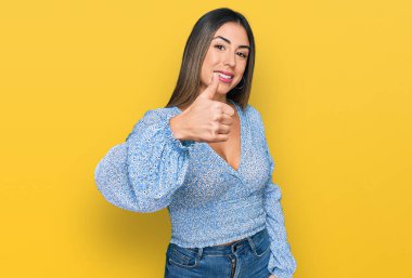Gündelik kıyafetler giyen genç İspanyol kadın elleriyle mutlu bir jest yapıyor. Kameraya bakıp başarıyı gösteren ifade. 