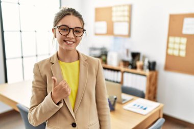 Genç esmer ergen ofiste iş elbisesi giyerek mutlu bir el hareketi yapıyor. Kameraya bakıp başarıyı gösteren ifade. 