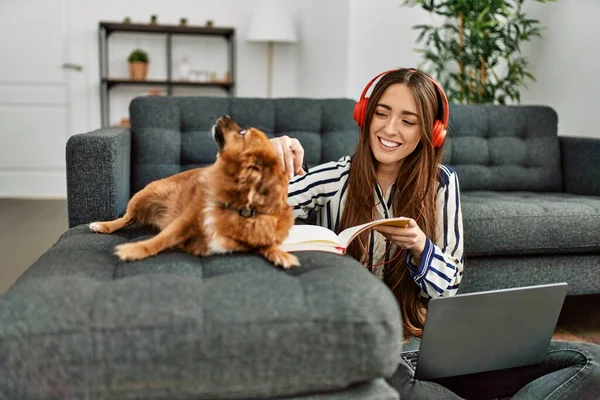 若いですヒスパニック女性使用してノートパソコン勉強床の上に座って犬とともに家に — ストック写真