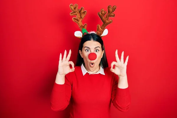 크리스마스 모자를 스페인 여자가 손가락으로 승인의 상징을 놀라고 충격받은 표정을 — 스톡 사진