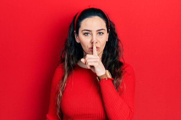Young hispanic woman wearing casual clothes asking to be quiet with finger on lips. silence and secret concept. 