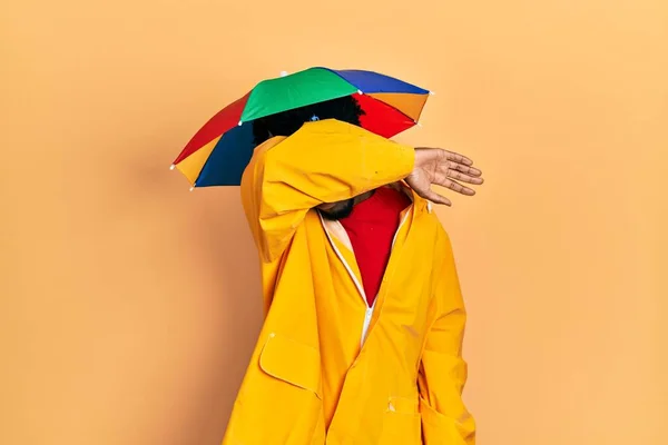 年轻的非洲裔美国人 身穿黄色雨衣 用胳膊蒙住眼睛 看起来严肃而忧郁 躲藏和拒绝的概念 — 图库照片