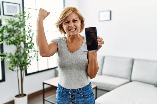 Medelålders Blond Kvinna Som Arbetar Håller Smartphone Visar Skärmen Irriterad — Stockfoto