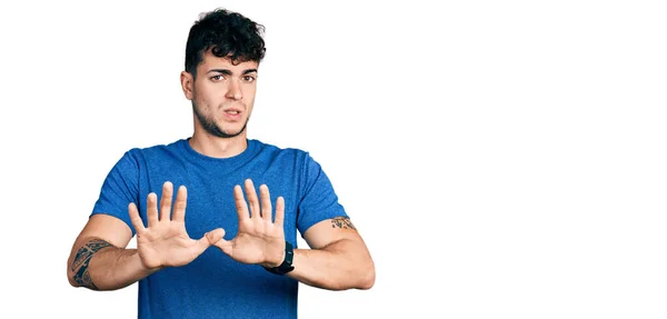 Jovem Hispânico Vestindo Camiseta Casual Afastando Mãos Palmas Das Mãos — Fotografia de Stock
