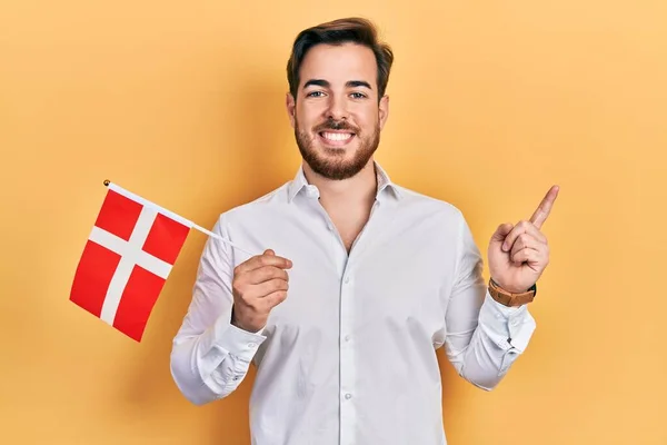 Handsome Caucasian Man Beard Holding Denmark Flag Smiling Happy Pointing — Zdjęcie stockowe