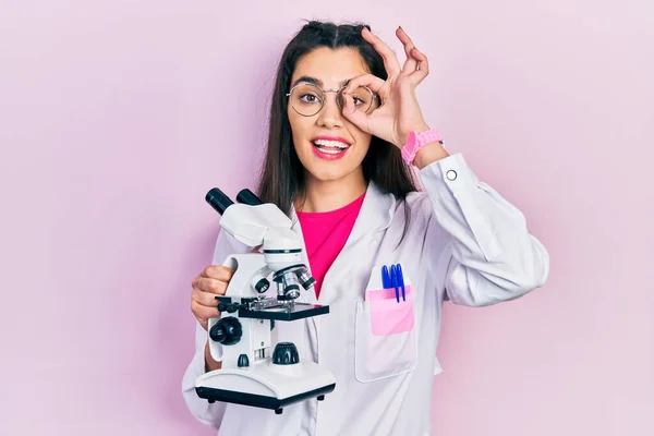 Молода Іспаномовна Дівчина Уніформі Вченого Тримає Мікроскоп Усміхнений Щасливий Робить — стокове фото