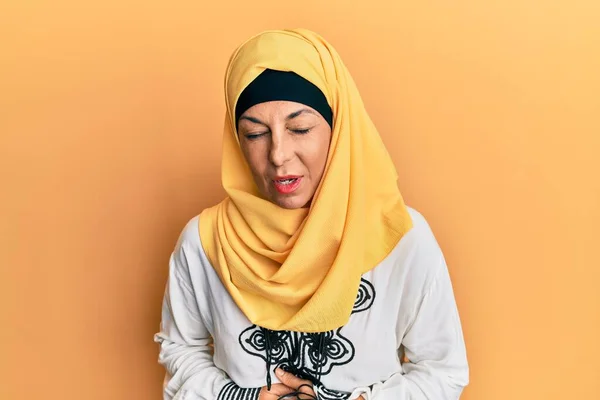 胃の上に手で伝統的なイスラム教のヒジャーブスカーフを身に着けている中世のヒスパニック女性ので 消化不良 痛みを伴う病気も感じている キャッシュ コンセプト — ストック写真