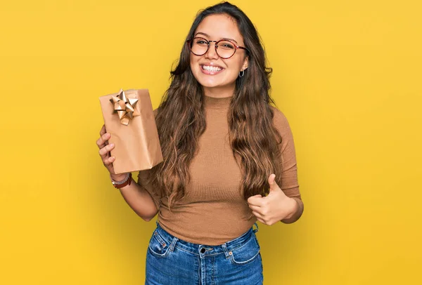 Jong Hispanic Meisje Houden Geschenk Glimlachen Gelukkig Positief Duim Omhoog — Stockfoto