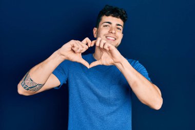 Gündelik kıyafetler giyen, aşık gülümseyen, elleriyle kalp sembolü yapan genç bir İspanyol. romantik kavram. 