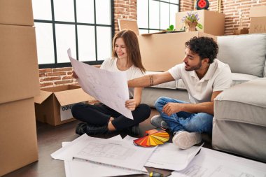 Erkek ve kadın, gülümseyen ve kendine güvenen bir çift yeni evinde boya rengi seçiyor.