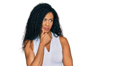 Orta yaşlı Afro-Amerikalı kadın, kolsuz gömlekli, kolsuz, çenesi çenesinde soru soran, düşünceli bir ifade takınıyor. Düşünceli bir yüzle gülümsüyor. şüphe kavramı. 