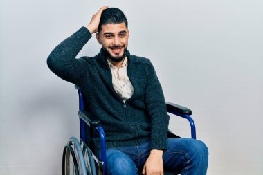 Tekerlekli sandalyede oturan sakallı yakışıklı adam şaşırmış ve soru soruyor. Şüpheyle kararsız, kafa kafaya düşünerek. Düşünceli kavram. 