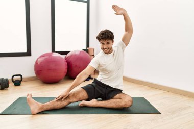 Genç İspanyol adam gülümsüyor spor merkezinde esniyor.