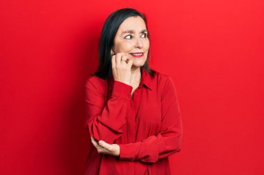 Orta yaşlı İspanyol kadın gündelik kıyafetler giyiyor. Stresli ve gergin görünüyor. Elleri ağızdan tırnak yiyor. anksiyete. 