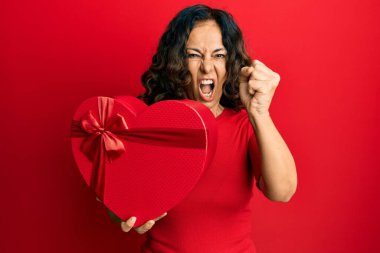 Orta yaşlı İspanyol kadın sevgililer günü hediyesini tutarken sinirlendi ve sinirlendi öfkeyle bağırdı, öfkeyle bağırdı ve el kaldırdı. 