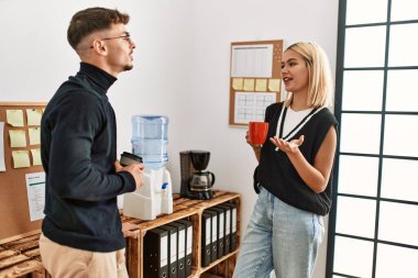 İki iş adamı gülümsüyor, ofiste kahve içiyorlar..